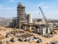Construction site of a cement plant in India with heavy equipment and kilns.